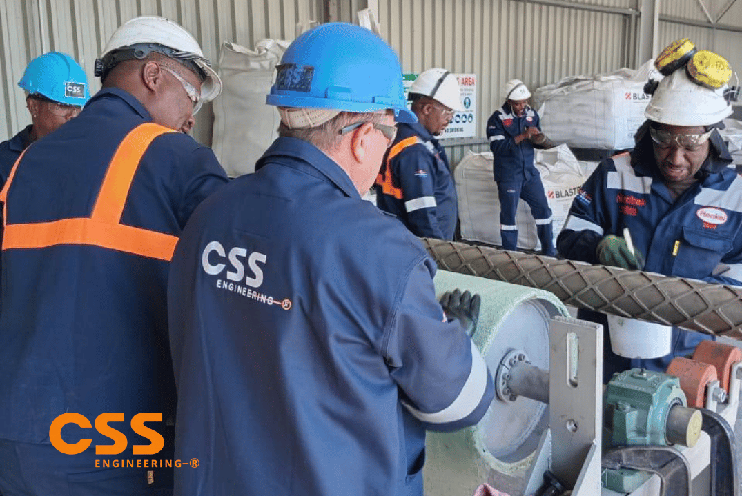 Technicians fitting wear-resistant lagging material onto industrial equipment
